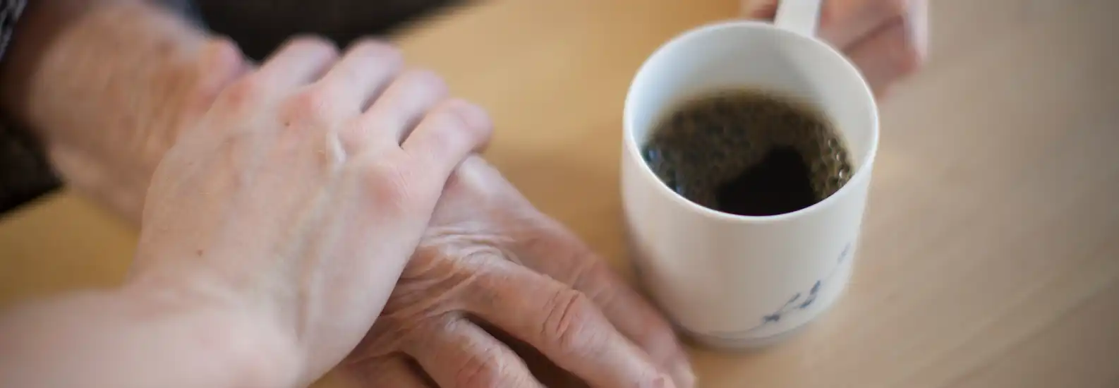 Några som håller varandra i handen medan de dricker en kopp kaffe.