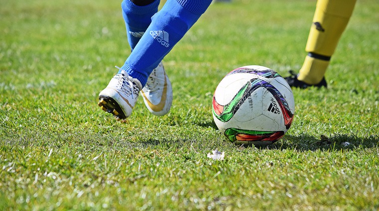 Bild på fotboll och fotbollspelares ben och fötter som spelar fotboll.